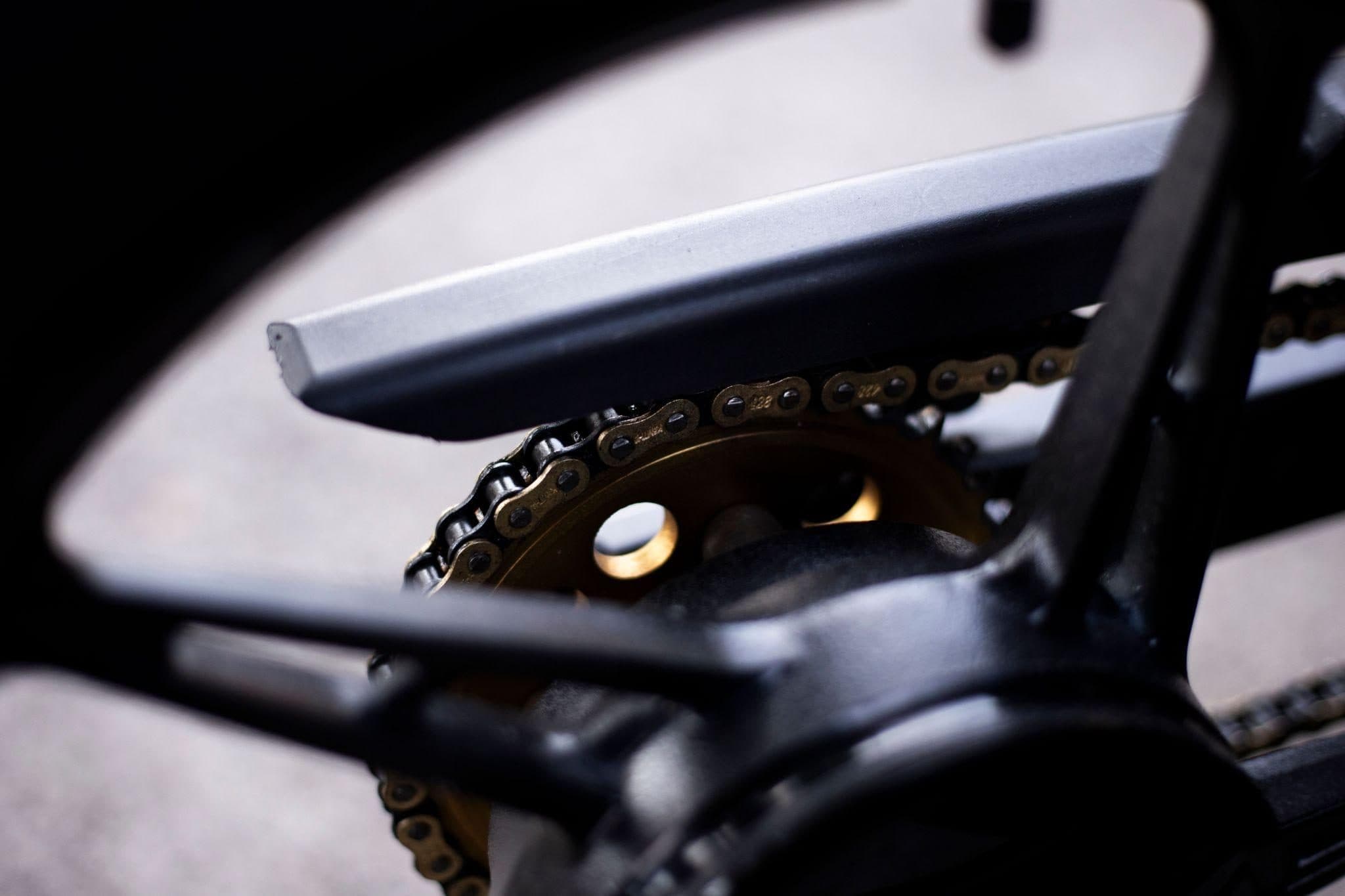Chaîne et couronne dorée d’une moto vues sous le bras oscillant